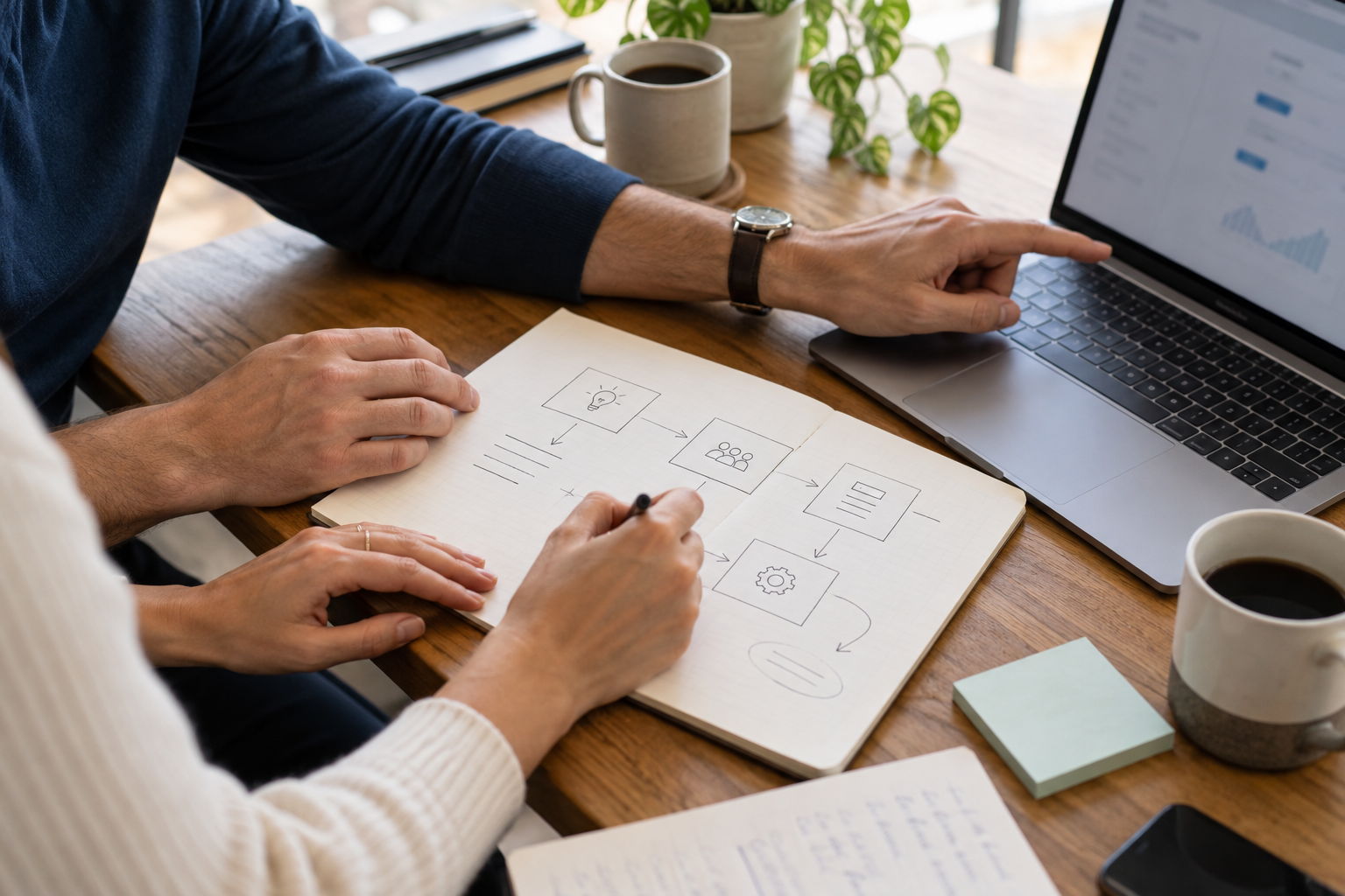 Colleagues reviewing a workflow sketch and laptop together